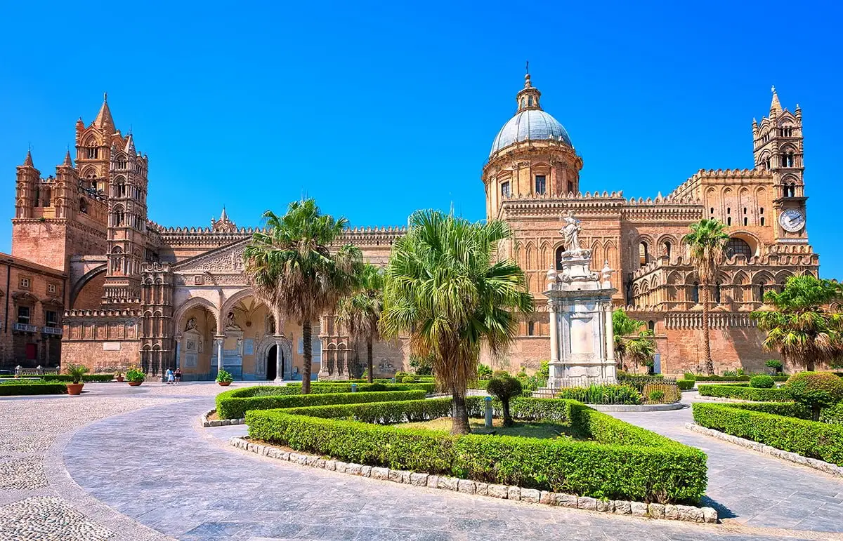 Palermo Cathedral with palm trees under blue sky in Sicily, Italy