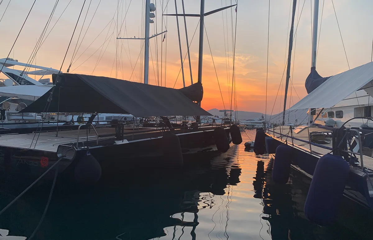 Luxury sailing yachts moored in the Port of St Tropez at sunset with reflections on calm Mediterranean waters. - Echonautique.com St Tropez Harbour at Sunset | Luxury Sailing Yachts in the Port