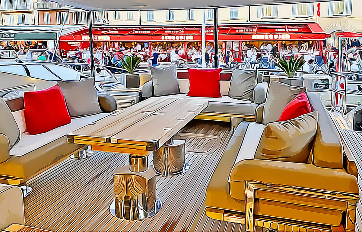 senequier-1200x771px - Echonautique.com Luxurious outdoor yacht lounge with beige seating, red and gray pillows, and a wooden coffee table on a striped deck. A lively marina backdrop with red awnings.